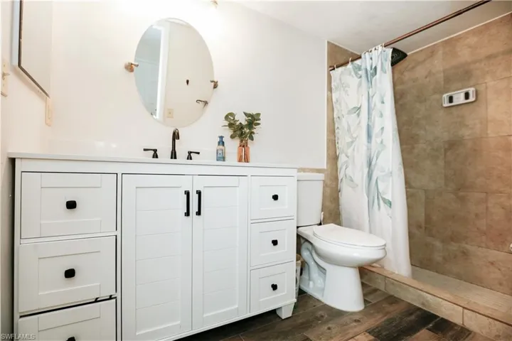Bathroom featuring vanity, curtained shower, wood-type flooring, and toilet