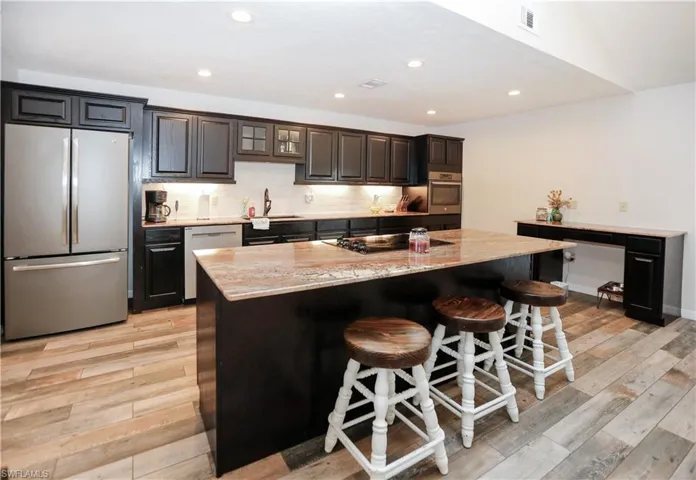 Kitchen with an island with sink, appliances with stainless steel finishes, a breakfast bar, and light hardwood / wood-style floors
