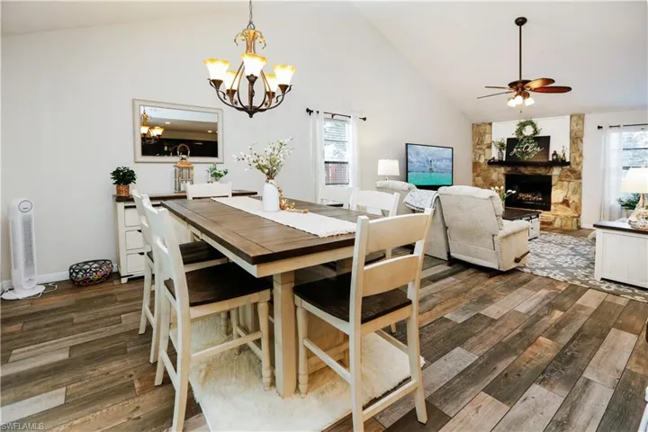 Dining room featuring a healthy amount of sunlight, high vaulted ceiling, dark hardwood / wood-style floors, and a fireplace