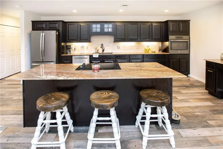 Kitchen featuring sink, appliances with stainless steel finishes, a kitchen bar, and a kitchen island with sink