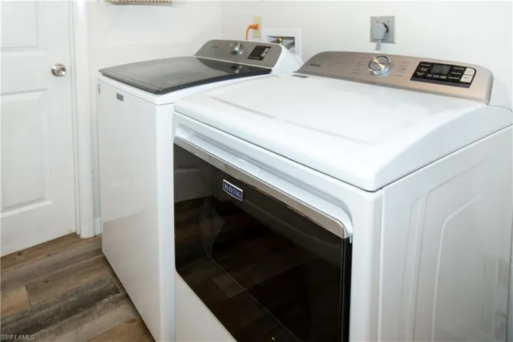 Laundry area featuring dark hardwood / wood-style flooring and washer and clothes dryer