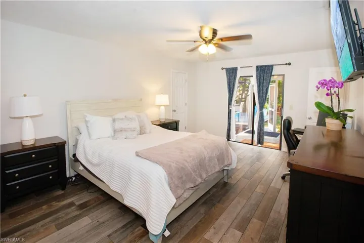 Bedroom featuring ceiling fan, access to exterior, and dark hardwood / wood-style flooring