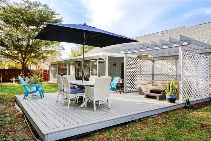 Wooden terrace featuring a hot tub, a pergola, and a sunroom