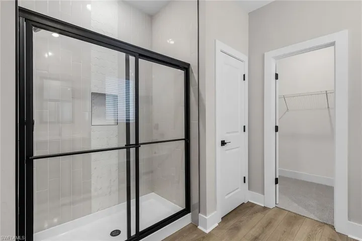 Bathroom featuring light wood-style flooring, a walk in closet, and a stall shower