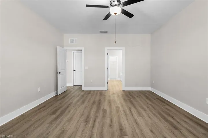 Unfurnished bedroom featuring wood finished floors, a ceiling fan, and ensuite bathroom