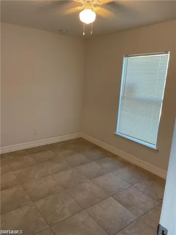 Spare room with a ceiling fan and light tile patterned floors