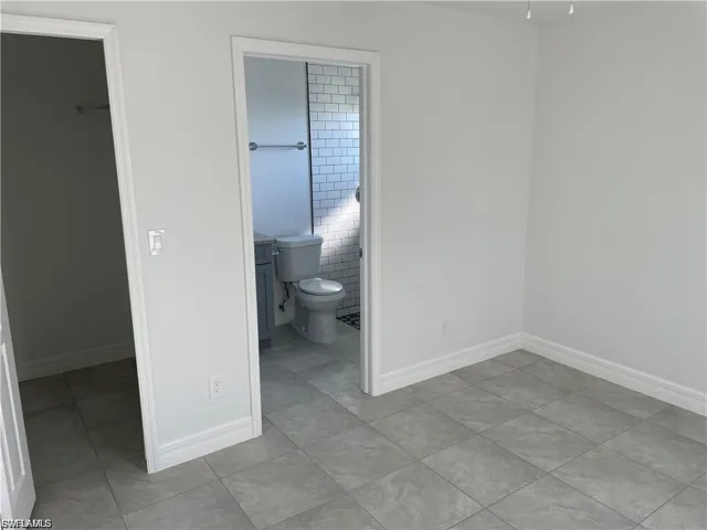 Unfurnished bedroom with a walk in closet, light tile patterned floors, and ensuite bathroom