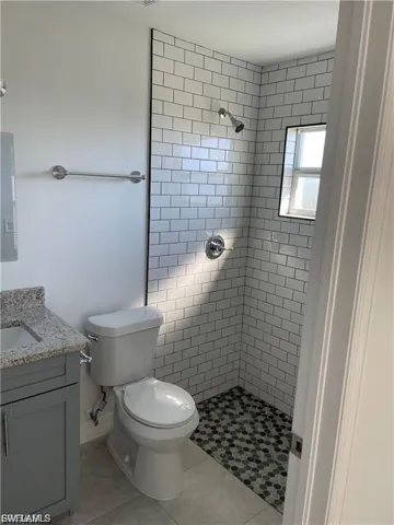 Bathroom featuring vanity, tiled shower, and light tile patterned flooring