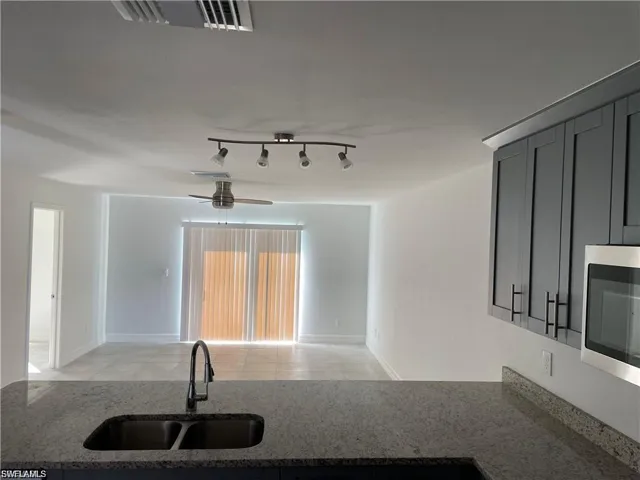 Kitchen featuring dark stone counters, open floor plan, stainless steel microwave, and a ceiling fan