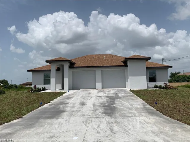 Prairie-style home with a front yard, stucco siding, and a garage