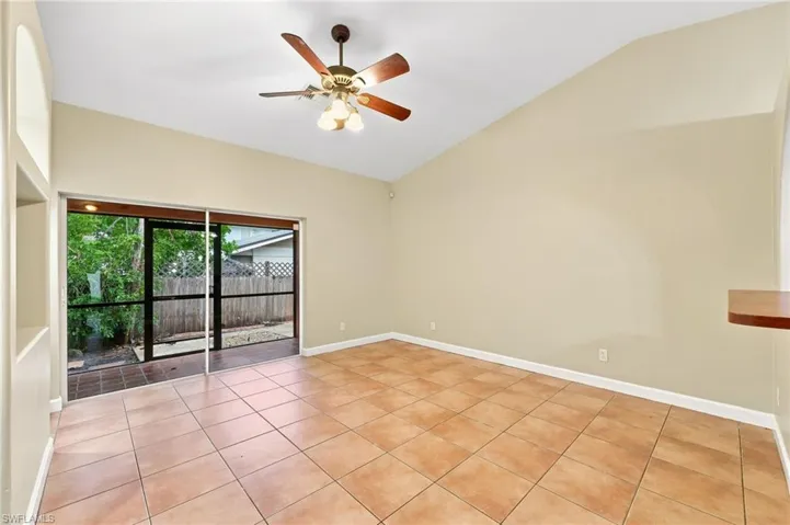 Spacious room featuring vaulted ceilings, a ceiling fan with light kit, and neutral wall tones