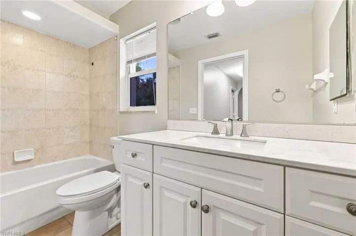 Spa-inspired primary bathroom featuring a white shaker-style vanity with dual sinks, quartz countertop, and polished chrome hardware