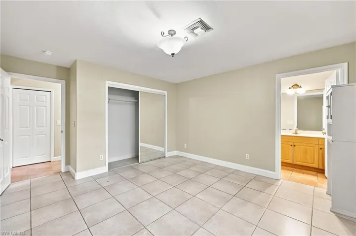 Spacious kitchen featuring tile flooring, ample cabinet storage, built-in refrigerator, and multiple entry points