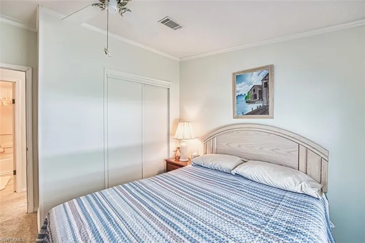 Carpeted bedroom with ornamental molding, a closet, and a ceiling fan