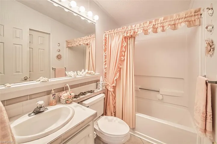 Bathroom with vanity, shower / bath combo, toilet, a textured ceiling, and tile patterned floors