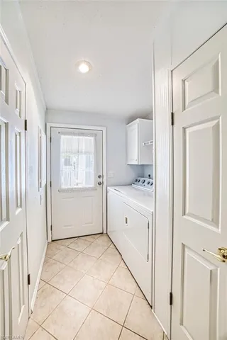 Laundry room with cabinet space, separate washer and dryer, light tile patterned floors, a textured ceiling, and ornamental molding