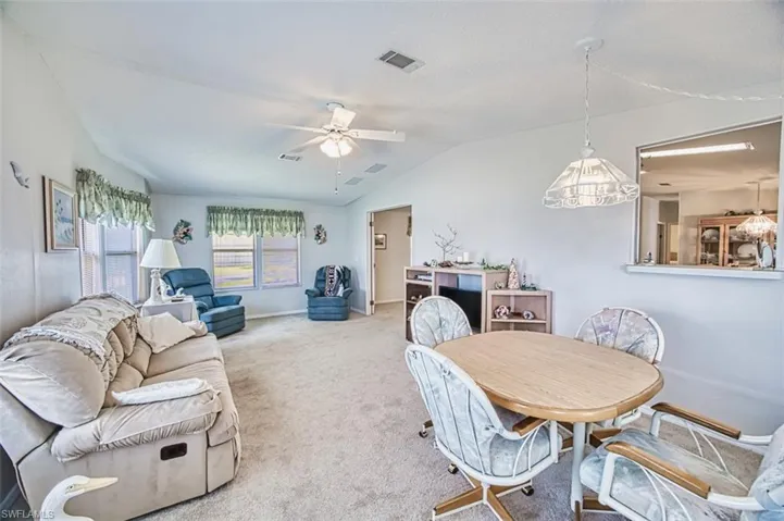 Dining space with ceiling fan, vaulted ceiling, carpet floors, and baseboards
