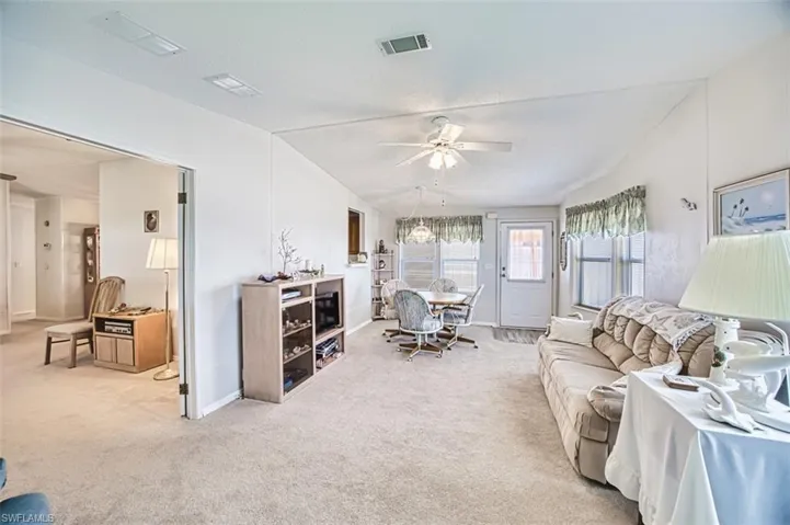 Living area featuring light colored carpet, a ceiling fan, baseboards, and a textured ceiling