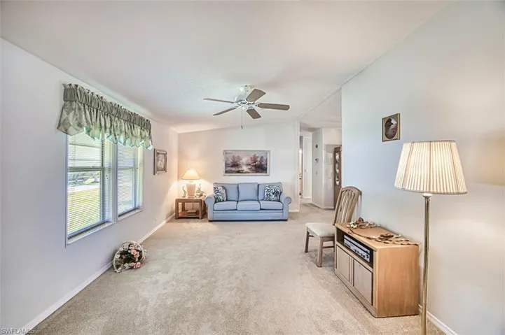 Living room with light carpet, ceiling fan, and baseboards