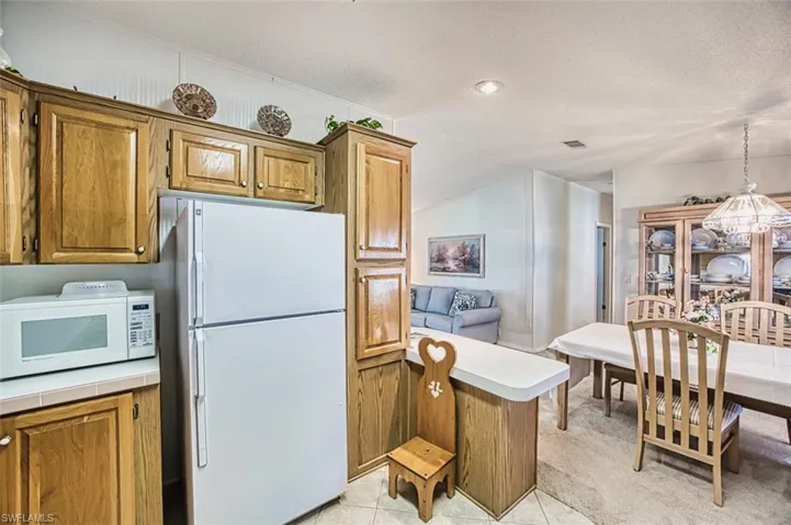 Kitchen with white appliances, brown cabinets, a textured ceiling, a peninsula, and light carpet