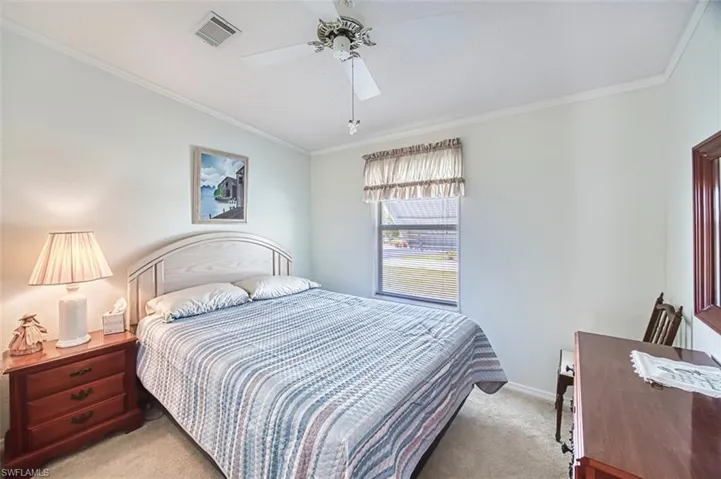 Bedroom with light carpet, ornamental molding, baseboards, and a ceiling fan