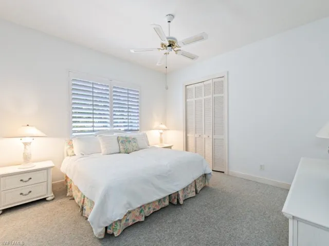 Bedroom with light carpet, ceiling fan, and a closet