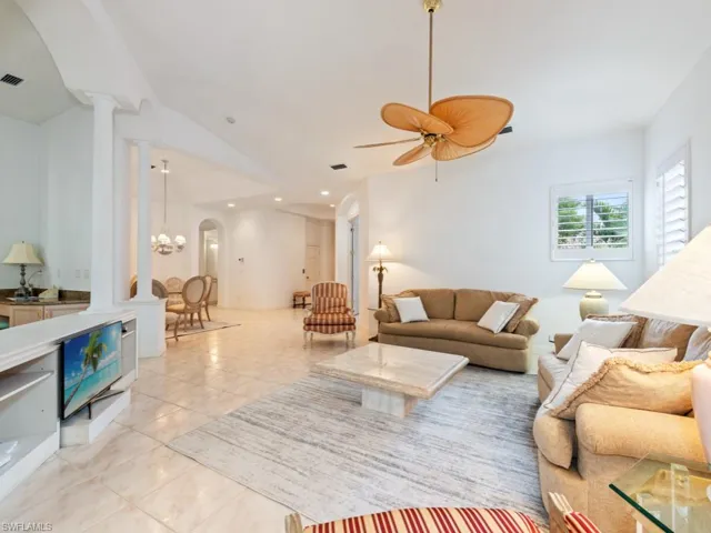 Living room featuring arched walkways, light tile patterned floors, vaulted ceiling, ceiling fan, and recessed lighting