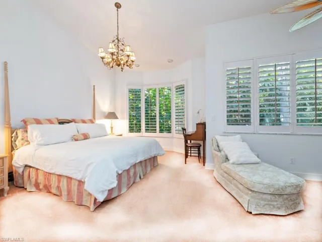 Bedroom featuring carpet flooring, lofted ceiling, and a chandelier