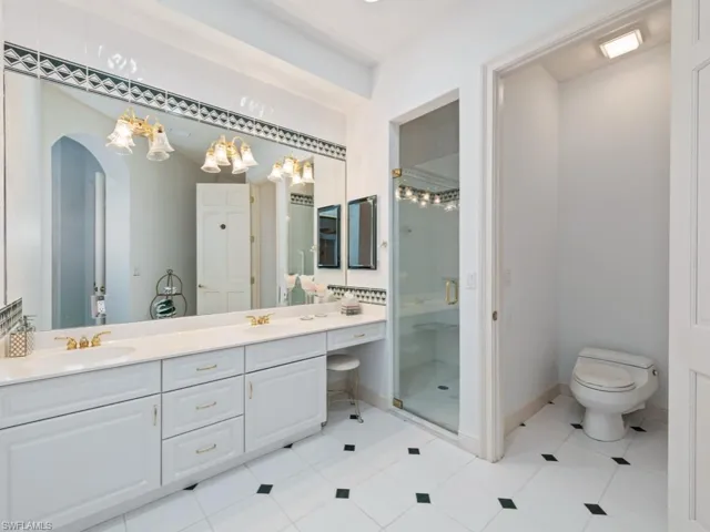 Bathroom featuring a shower stall, double vanity, light tile patterned floors, and a chandelier