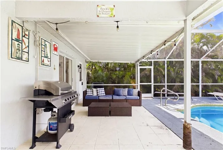 Screened lanai featuring a covered patio, tiled flooring, and an in-ground swimming pool with handrails