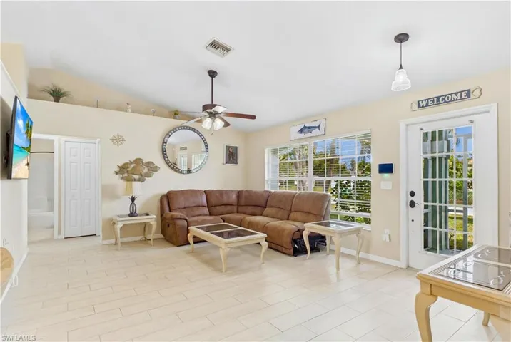 Spacious living area featuring tile flooring, vaulted ceilings, and a ceiling fan with integrated lighting