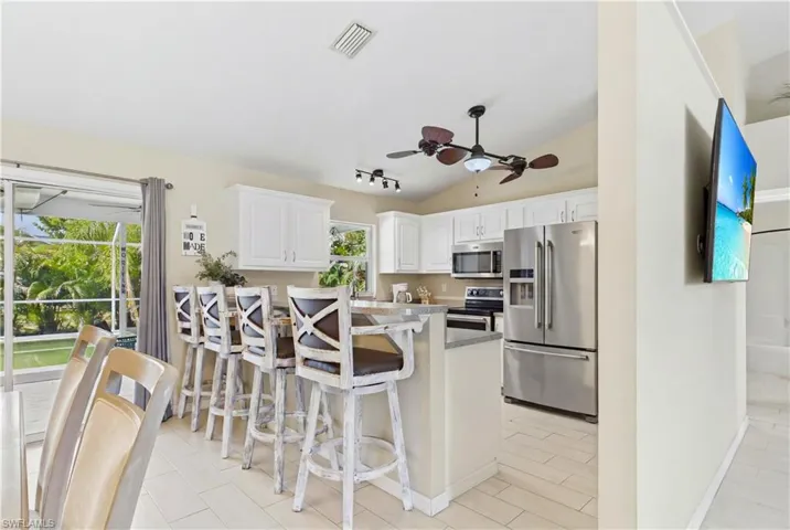 Kitchen featuring white cabinetry, stainless steel appliances, a breakfast bar with seating, and tile flooring