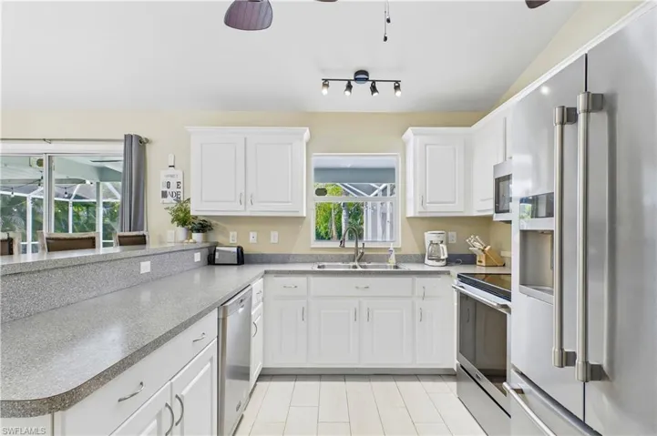 Kitchen featuring white cabinetry, light-toned countertops, and stainless steel appliances