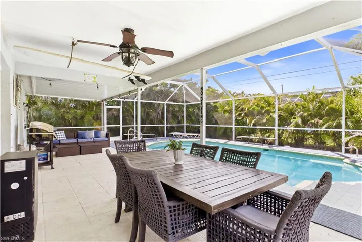 Screened lanai featuring a covered patio, ceiling fan with integrated lighting, and an in-ground swimming pool