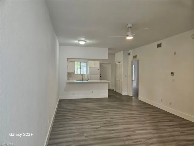 Empty room with dark hardwood / wood-style flooring, sink, and ceiling fan