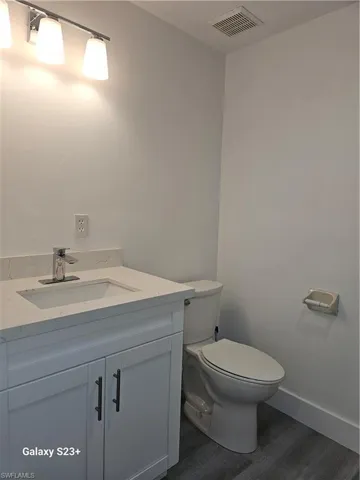 Bathroom featuring hardwood / wood-style flooring, vanity, and toilet