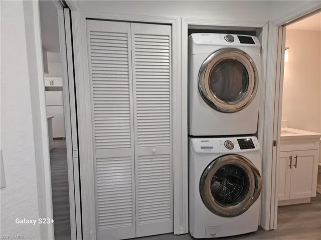 Clothes washing area with stacked washer / dryer and hardwood / wood-style floors