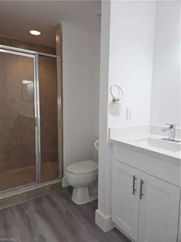 Bathroom with walk in shower, wood-type flooring, vanity, and toilet