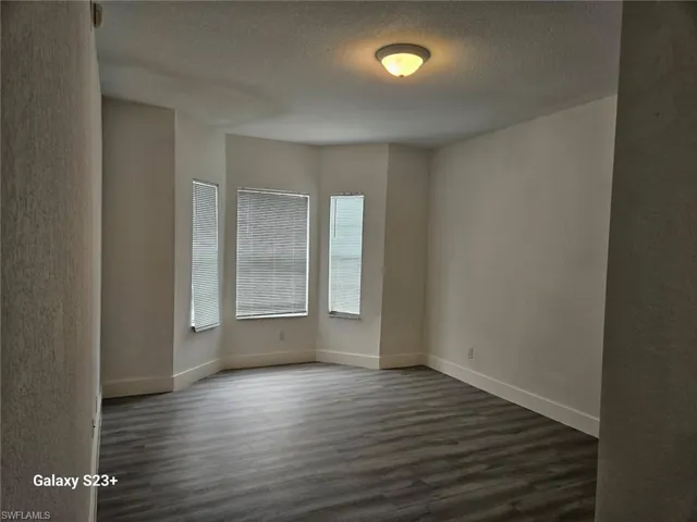 Unfurnished room with dark hardwood / wood-style floors and a textured ceiling