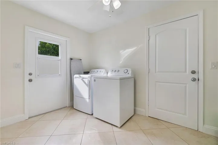 Washroom featuring washing machine and dryer, light tile patterned flooring, and a ceiling fan