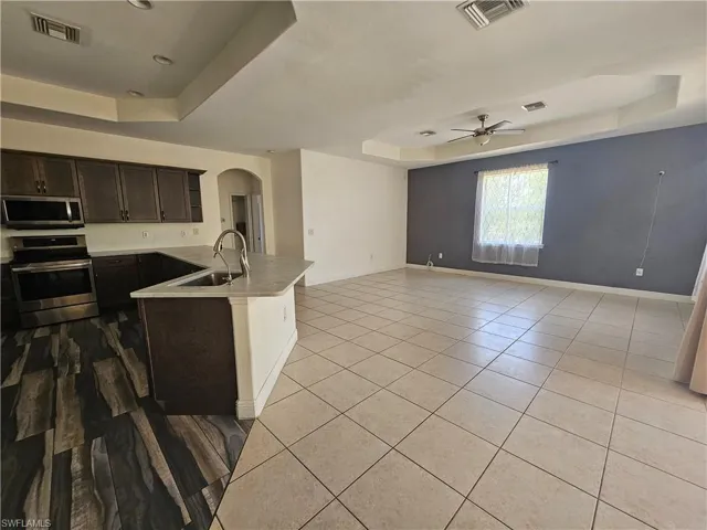 Kitchen with stainless steel appliances, sink, dark brown cabinets, and a raised ceiling