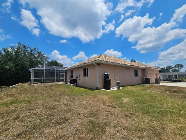 Rear view of property featuring a yard and a lanai