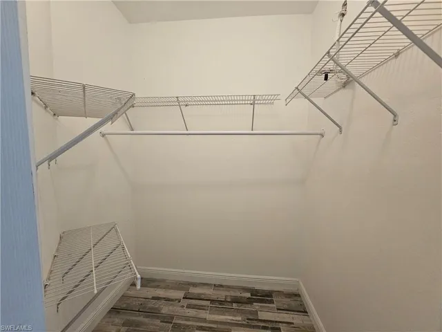 Walk in closet with wood-type flooring