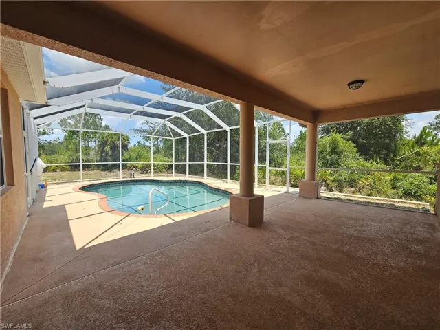 View of pool featuring a patio and glass enclosure