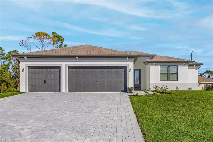 Prairie-style home featuring a front yard, decorative driveway, stucco siding, an attached garage, and roof with shingles