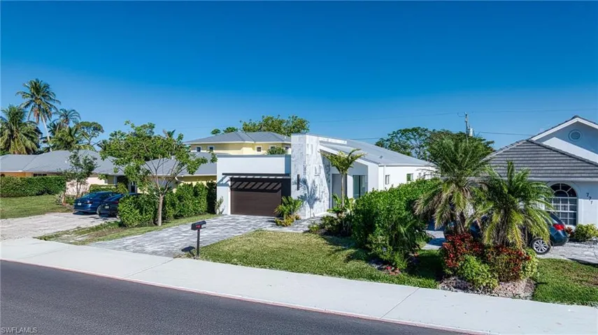 View of front facade with decorative driveway, a front yard, and stucco siding