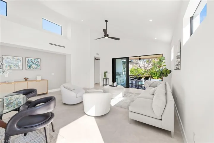 Living room featuring ceiling fan, a high ceiling, baseboards, and recessed lighting
