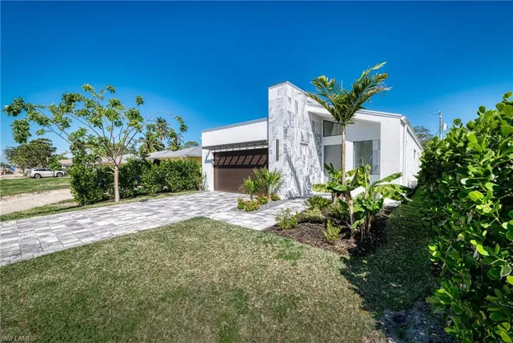 View of front of house featuring decorative driveway, an attached garage, a front yard, and stucco siding