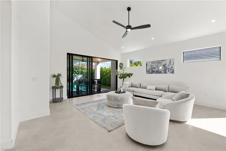 Living area with ceiling fan, high vaulted ceiling, baseboards, and recessed lighting