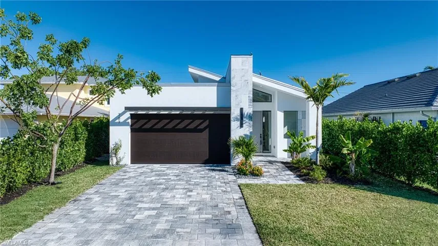 View of front of home featuring decorative driveway, a front lawn, and stucco siding
